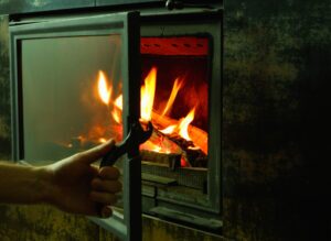 homeowner opening or closing fireplace glass doors to keep their home warm safe and energy efficient